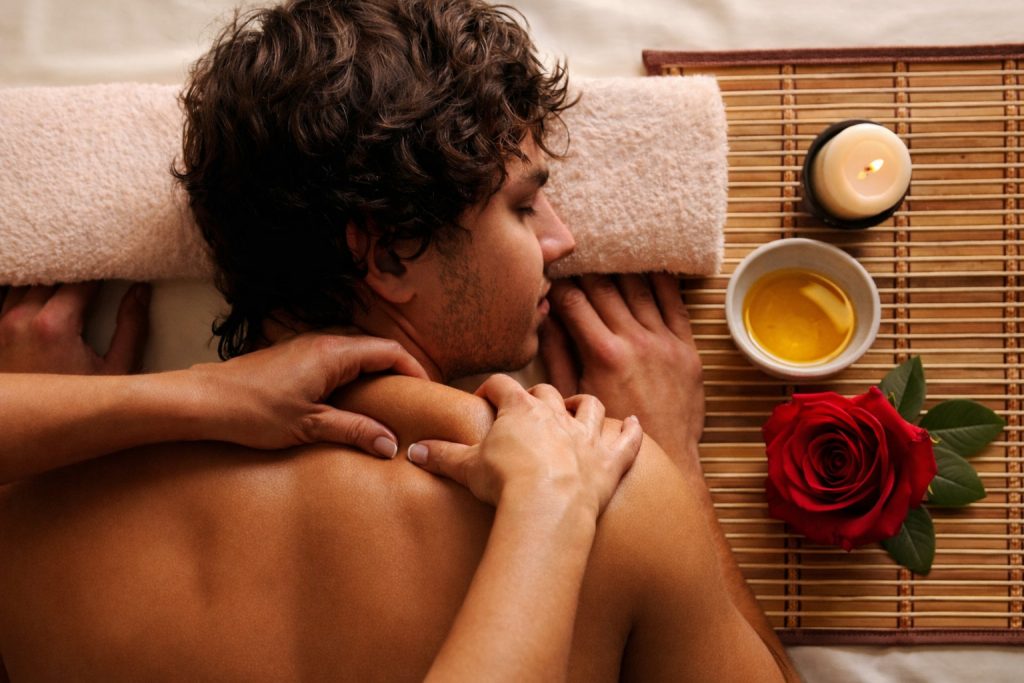 A guy enjoying a sensual massage from his partner